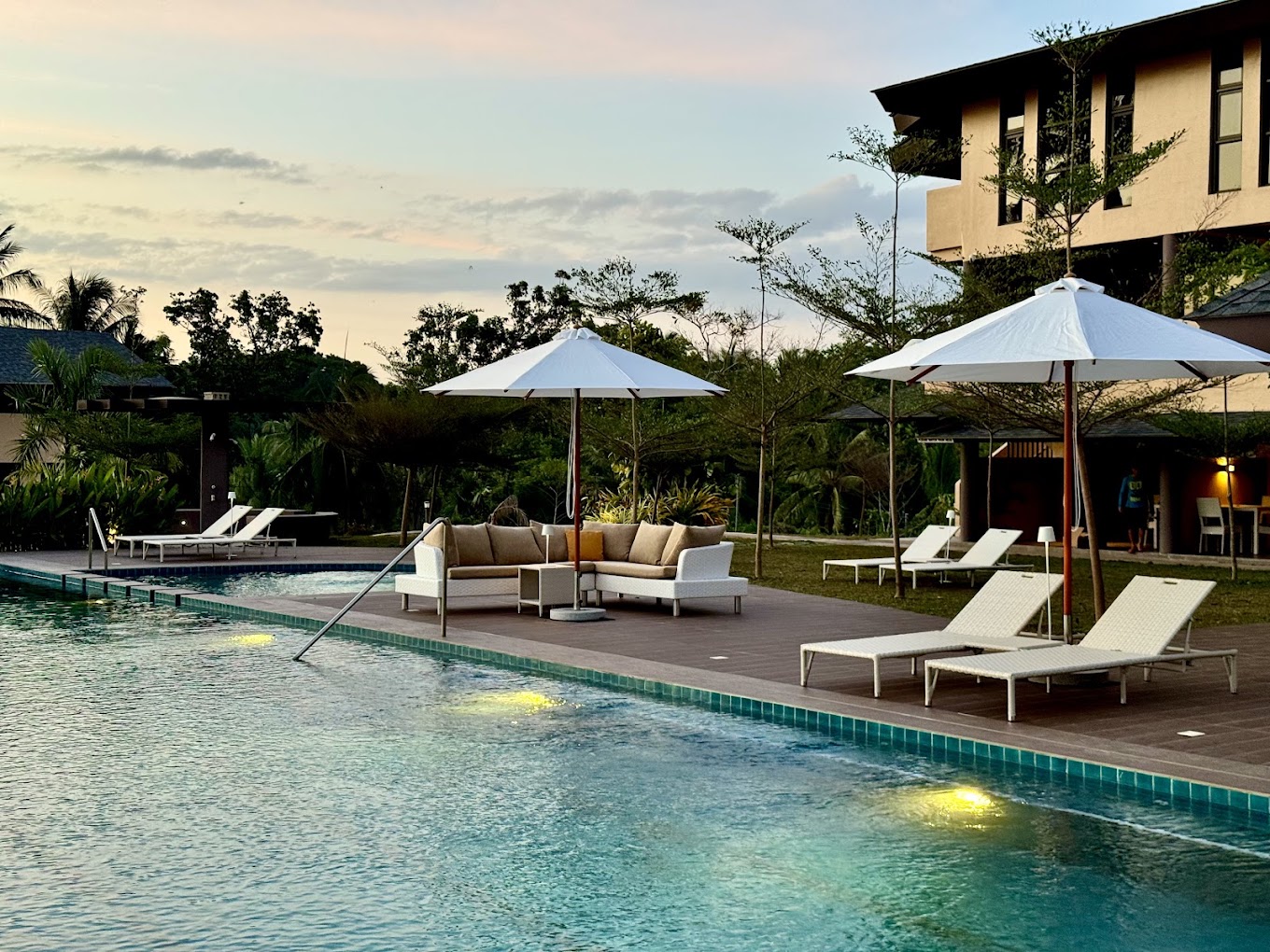Pool deck at sunset with loungers and umbrellas